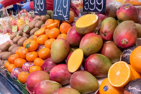 Frischer Obststand mit Mangos, Orangen und Kiwis in der Markthalle Mercat de la Boquerìa am Placa de Sant Josep in Barcelona, Spanien