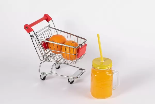 Frischer Orangensaft und Orangen in Einkaufswagen stehen für den Kauf von gesunden Nahrungsmitteln