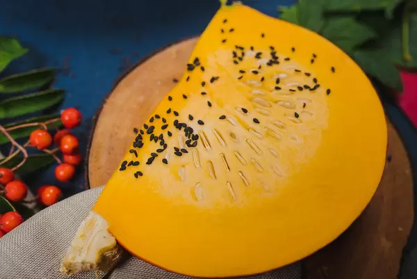 Frischer reifer Kürbis mit schwarzen Samen drauf gestreut