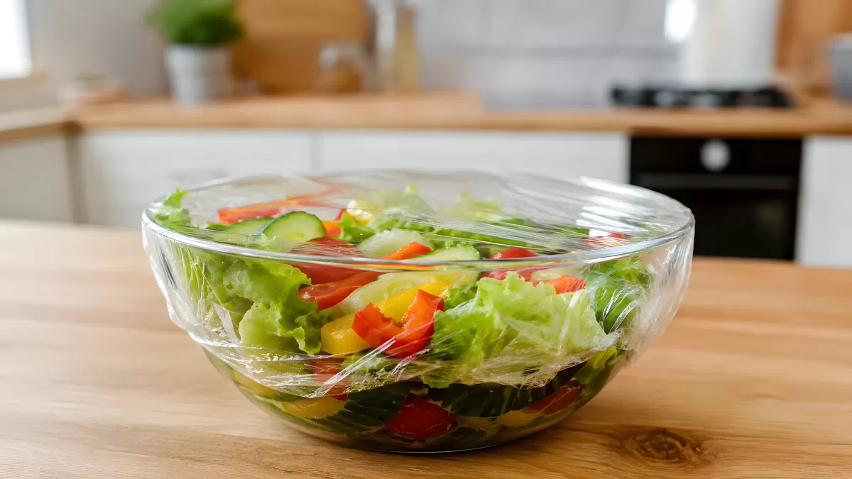 Frischer Salat in Glasschüssel mit Frischhaltefolie