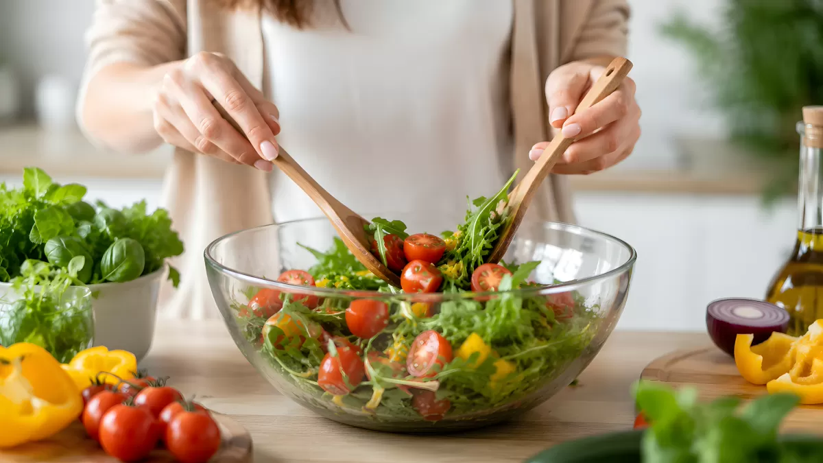 Frischer Salat wird in Glasschüssel zubereitet