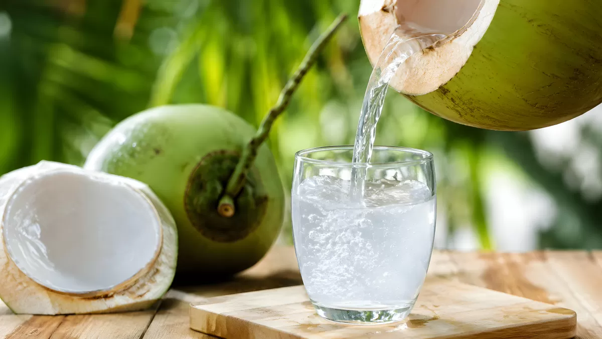 Frisches Kokoswasser wird in ein Glas gegossen