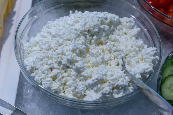 Frischkäse als vegetarischer Brotaufstrich, in einer Glasschale mit Löffel, gekühlt auf crushed-ice am Büfetttisch