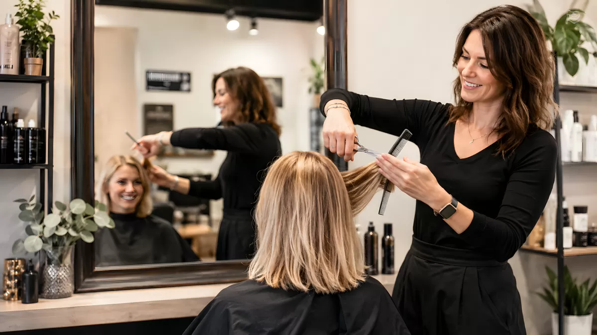 Friseurin stylt Haar der Kundin im modernen Salon