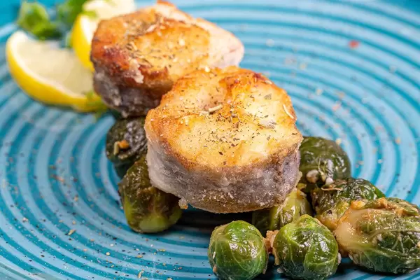 Fritierter Fisch mit Zitrone, Rosenkohl und Gewürzen in der Nahaufnahme