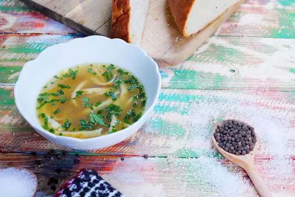 Frittatensuppe, beef broth with sliced pancakes, salt and pepper on a wooden vintage table (Flip 2019)