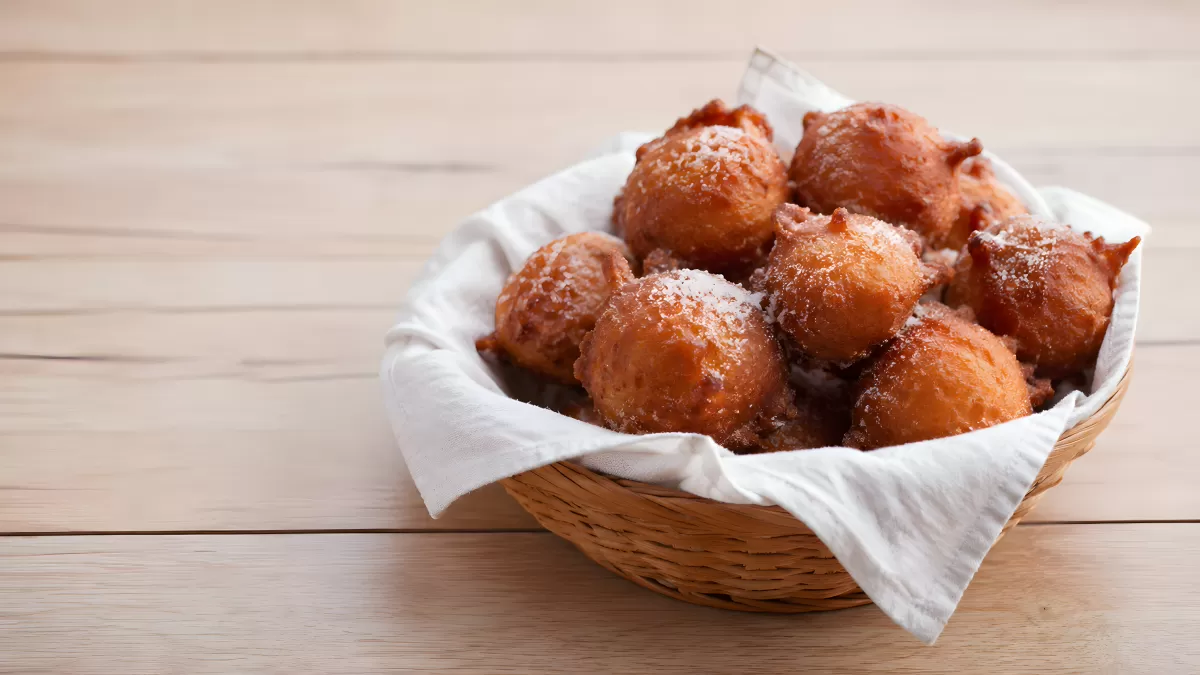 Frittierte holländische Teigbällchen mit Puderzucker im Weidenkorb