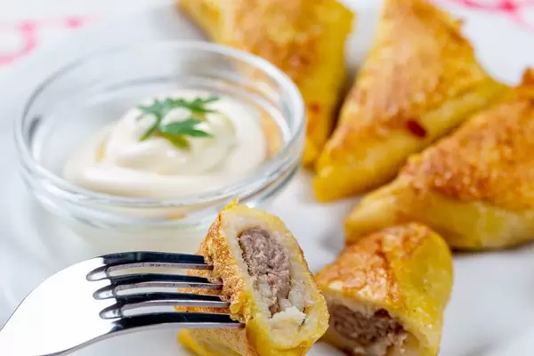 Frittierte Pfannkuchen mit Hackfleischfüllung und weißer Sauce