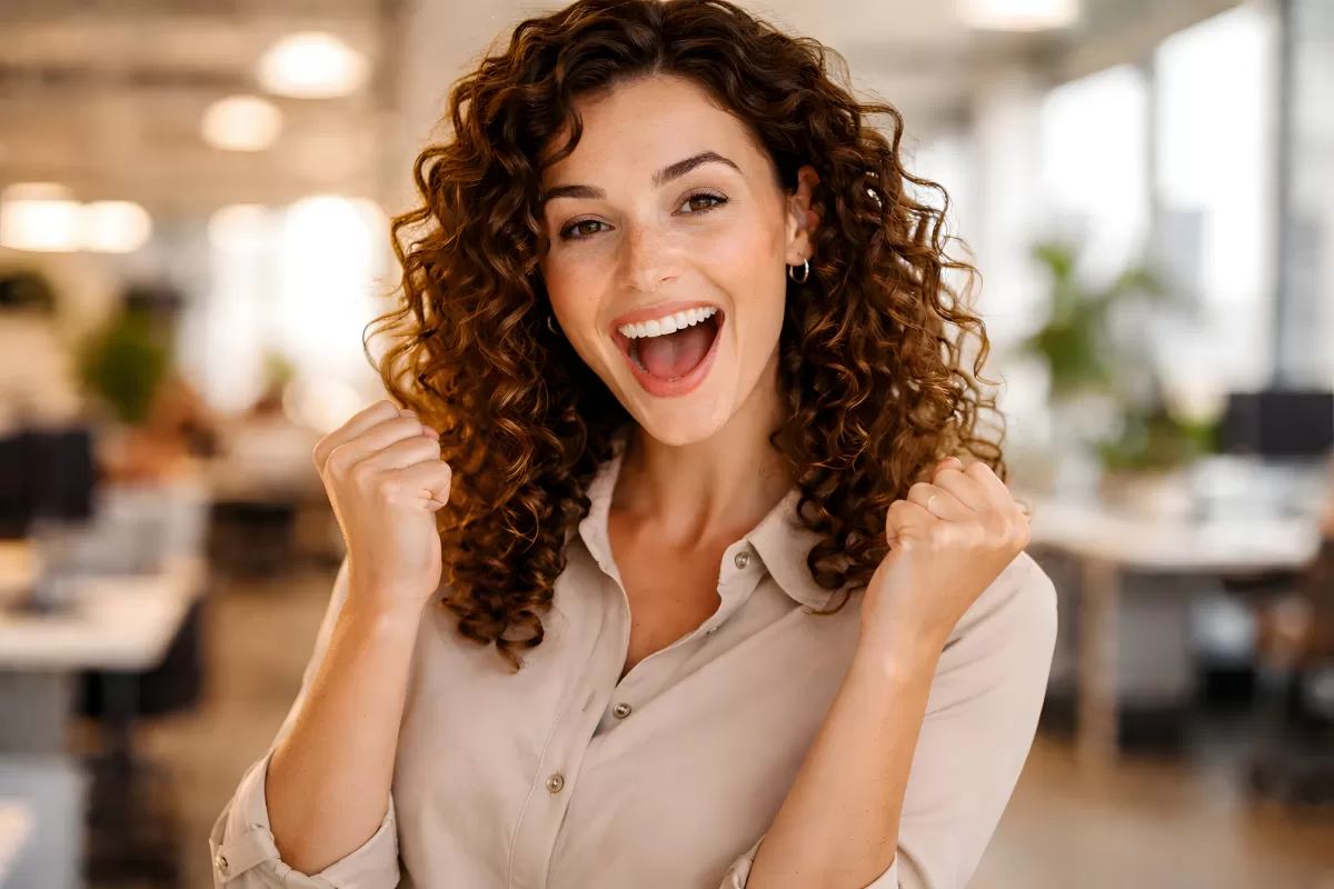 Fröhliche, gelockerte Frau lacht strahlend in die Kamera