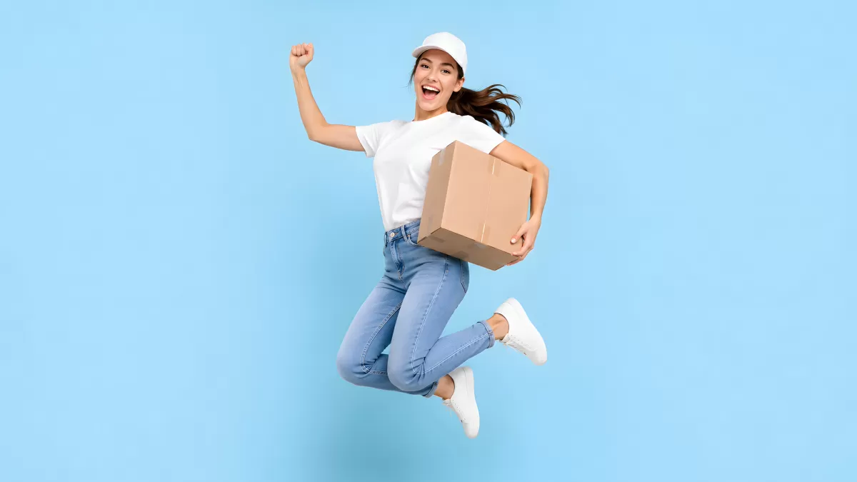 Fröhliche Lieferantin springt mit Paket in der Hand