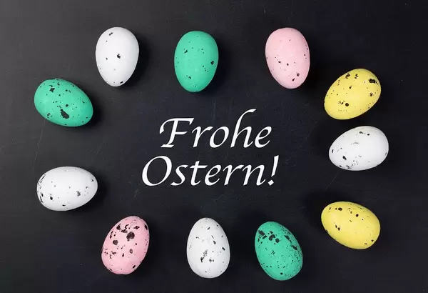 Frohe Ostern - bunte Ostereier umrunden die Schrift auf schwarzem Hintergrund
