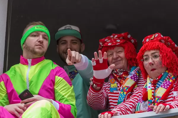 Fröhliche Zuschauer am Fenster in typischen Karnevalskostümen am Rosenmontag in Köln