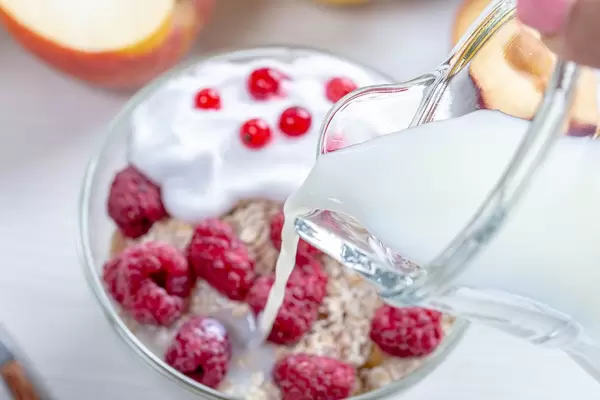From a glass jug pour milk into oatmeal with fruit (Flip 2019)