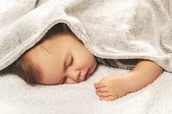 From under the gray plaid you can see the head and the handle of a cute little boy child