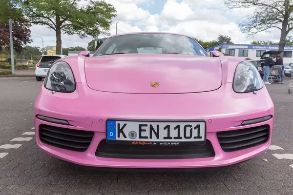 Front view of a Porsche 718 Cayman sports car in pink, at a German parking lot