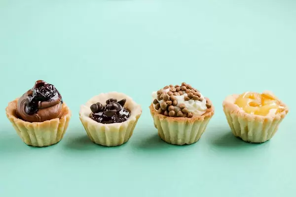 Front view of mini cake tarts. Desserts. Blue background