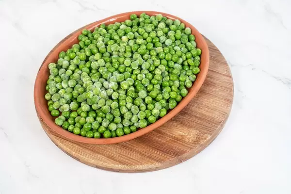 Frozen Green Peas in the bowl above white background (Flip 2019)