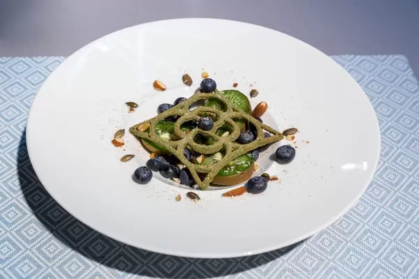 Früchtedessert mit Heidelbeeren, Kiwischeiben und Nüssen mit kunstvollem Gebäck