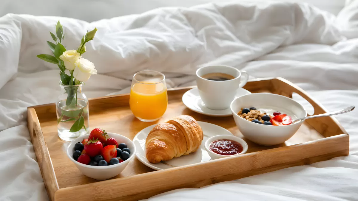 Frühstückstablett im Bett mit Croissant und Kaffee