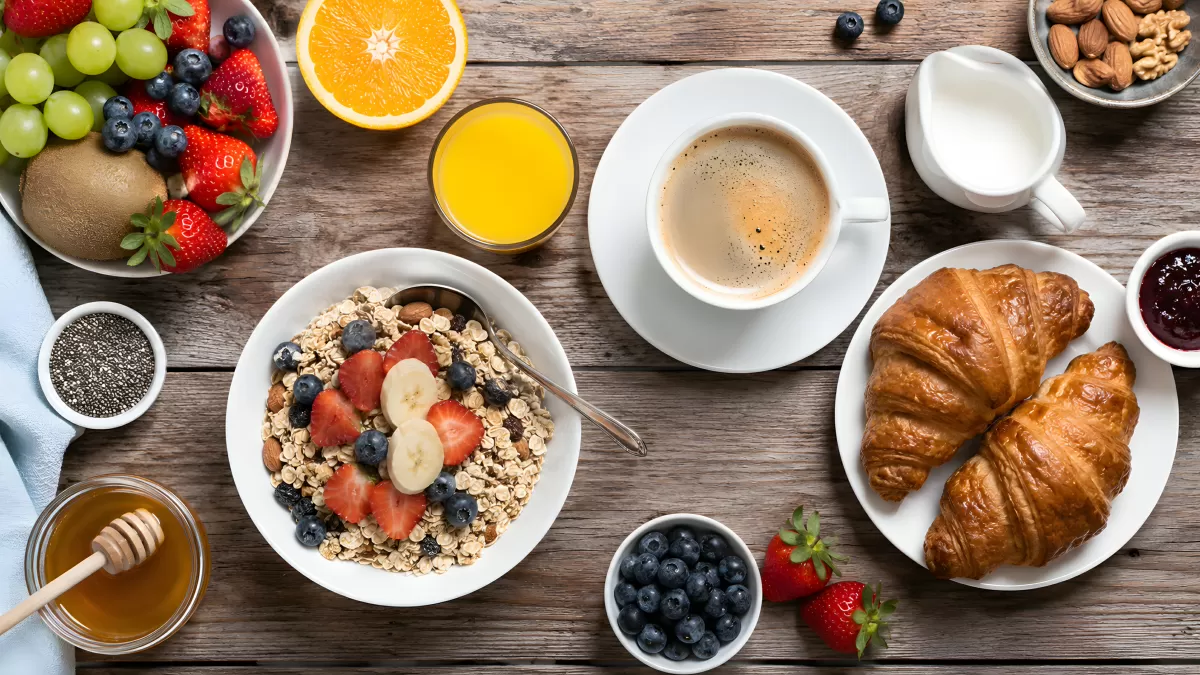 Frühstückstisch mit Müsli, Croissants und frischem Obst