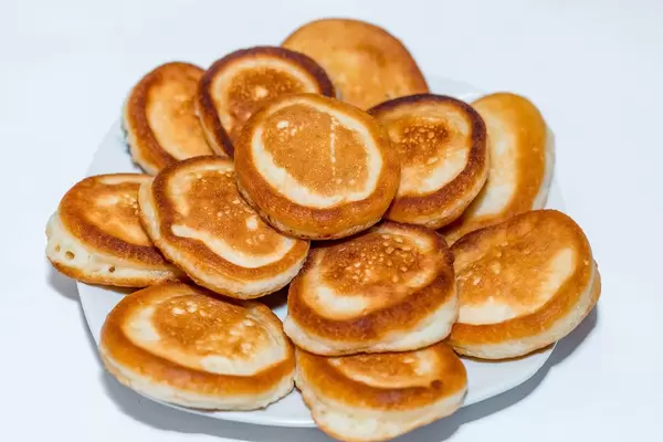 Frühstück aus selbstgemachten, dunkel gebratenen Pfannkuchen auf Teller gestapelt