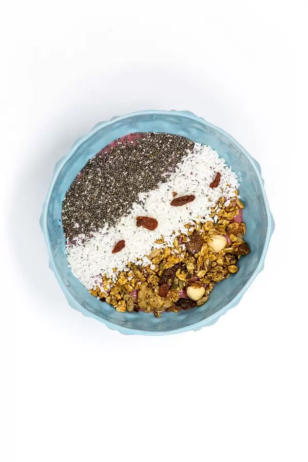 Frühstück - Granola Nuss Knuspermüsli mit Kokosraspeln, Chiasamen und Gojibeeren in einer Schüssel - Aufsicht