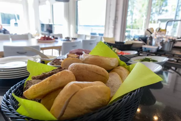 Frühstücksbüffet mit aufgeschnittenen Brötchen in einem blauen Korb im Hotel