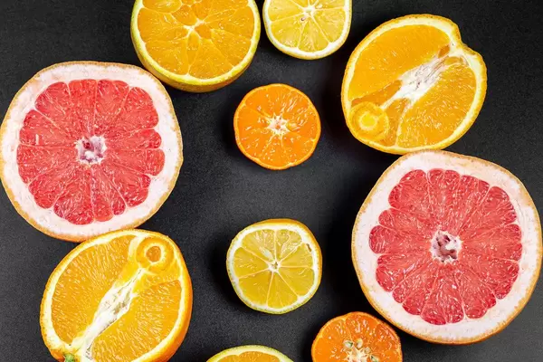 Fruit background with half a grapefruit, orange, lemon and mandarin on a black background, top view (Flip 2020)