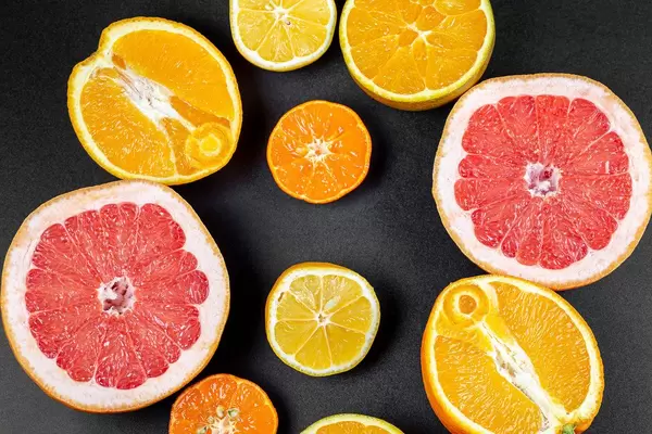 Fruit background with half a grapefruit, orange, lemon and mandarin on a black background, top view
