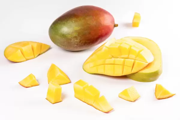 Fruit background with whole and chopped mango pieces