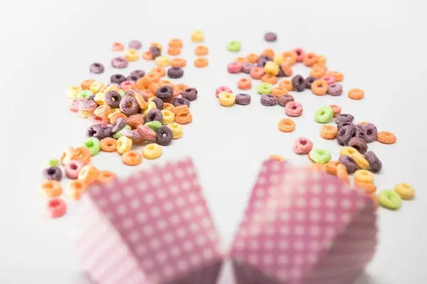 Fruit loops and pink cardboard cups on a white surface