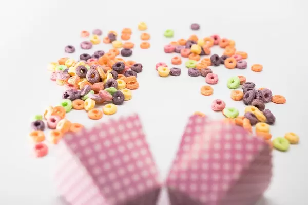 Fruit Loops fallen aus pinken Snackschachteln auf weißem Untergrund