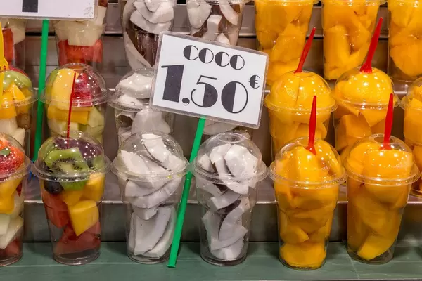 Fruit salad with coconut, kiwi, mango and melon is sold as streetfood in plastic boxes at indoor market Mercat de la Boqueria in Barcelona, Spain