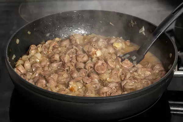 Frying pan with fried chicken hearts and onions, cooking process