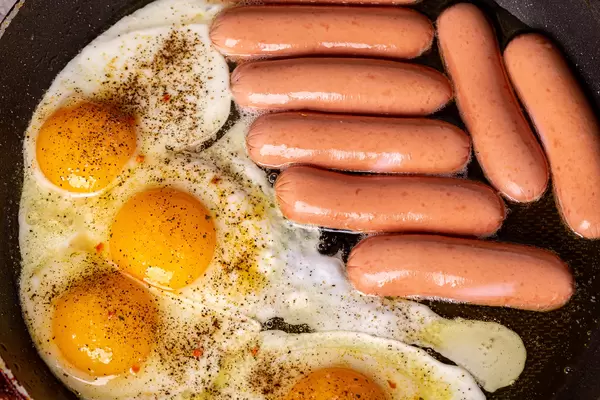 Frying pan with fried eggs and sausages, breakfast cooking concept