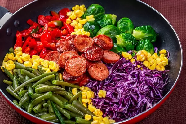 Frying pan with vegetables and sausages