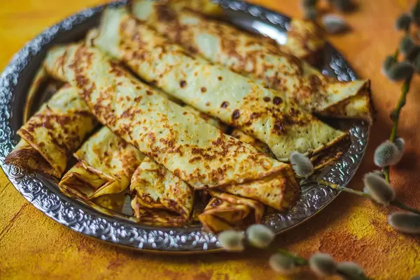 Frying Pancakes With Chocolate Filling On Orange Background Close Up