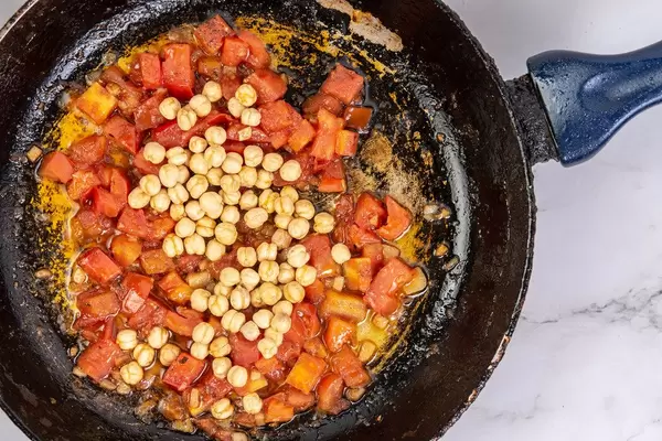 Frying sliced Tomato with Chickpeas in the frying pan
