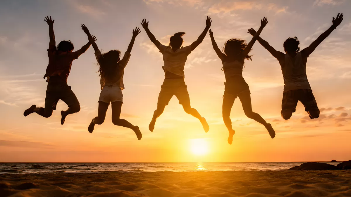 Fünf Freunde springen bei Sonnenuntergang am Strand