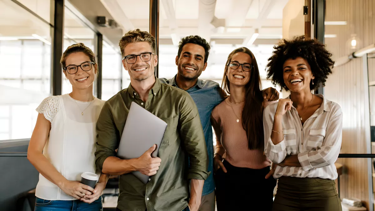 Fünf junge Kollegen lachen gemeinsam im Büro