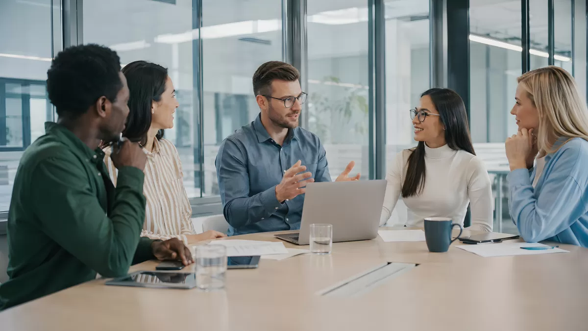 Fünf Kollegen im Büro-Meeting mit Laptop