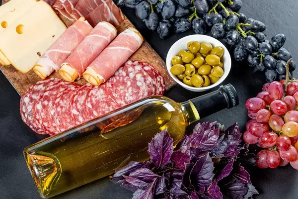 Full bottle of white wine with traditional snack on black background. Top view (Flip 2019)