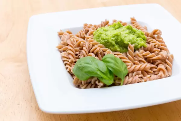 Full grain fussili pasta with green pesto and basil leaves