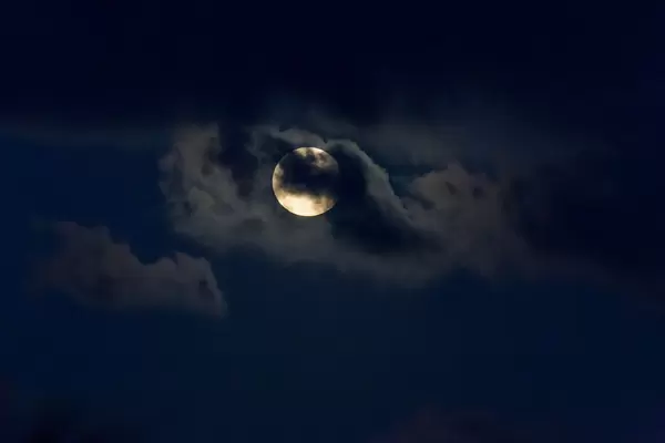 Full moon partially covered by clouds