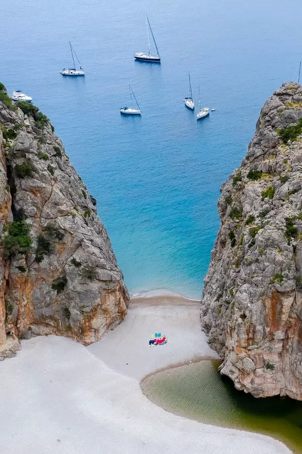 Fünf Segelboote und ein Motorboot vor dem Strand von Cala de sa Calobra auf Mallorca. Luftaufnahme