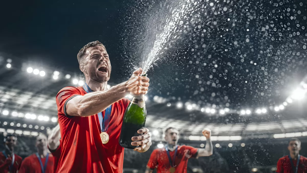 Fußballspieler feiert Sieg mit Champagner im Stadion