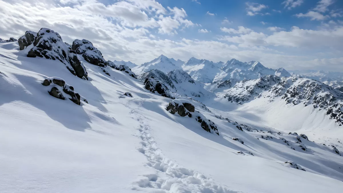 Fußspuren im Schnee führen durch alpine Berglandschaft