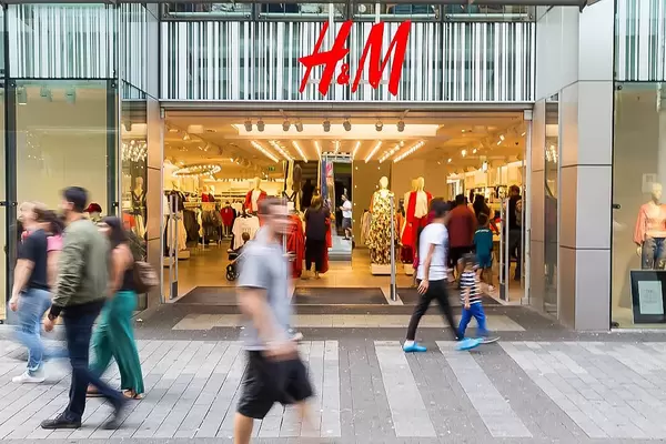 Fußgänger vor einer Bekleidungskette und Textilgeschäft in Deutschland