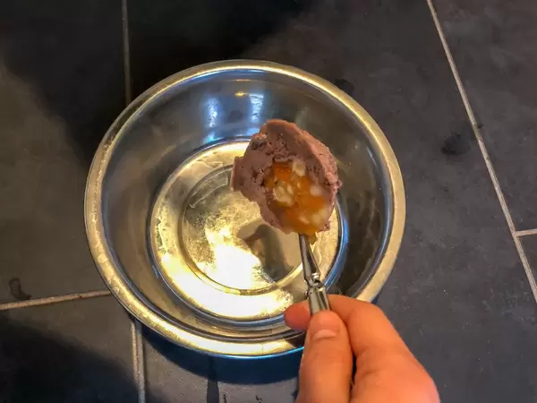 Futterpastete für Hunde wird mit Löffel in Futternapf aus Metall gegeben