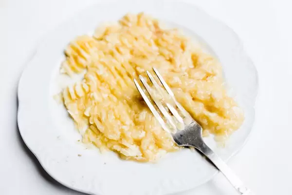 Gabel liegt in damit hergestelltem Bananenmus vor weißem Hintergrund